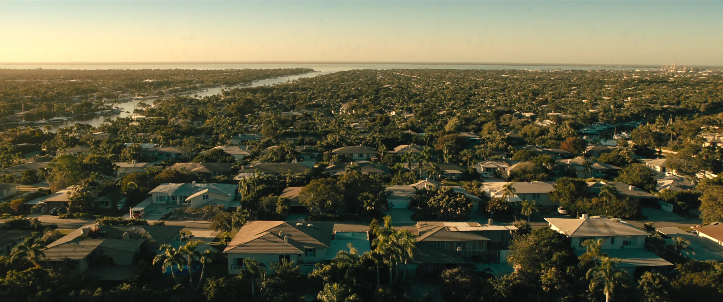 Aerial view of a South Florida waterfront neighborhood of single-family homes and canals at golden hour